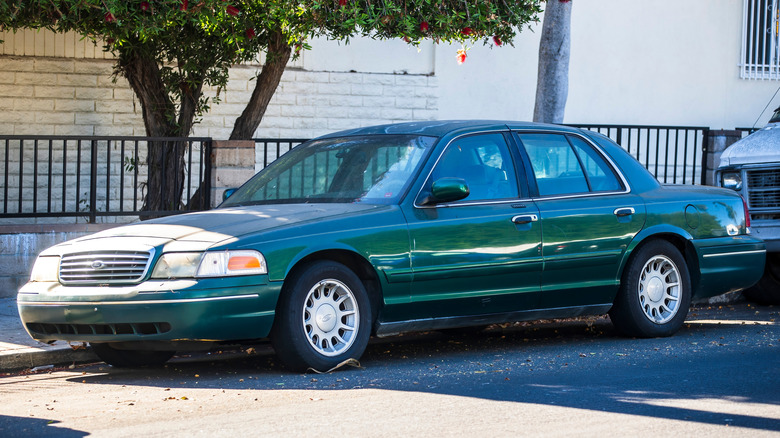 Front 3/4 view of gray Ford Crown Victoria parked on city street.