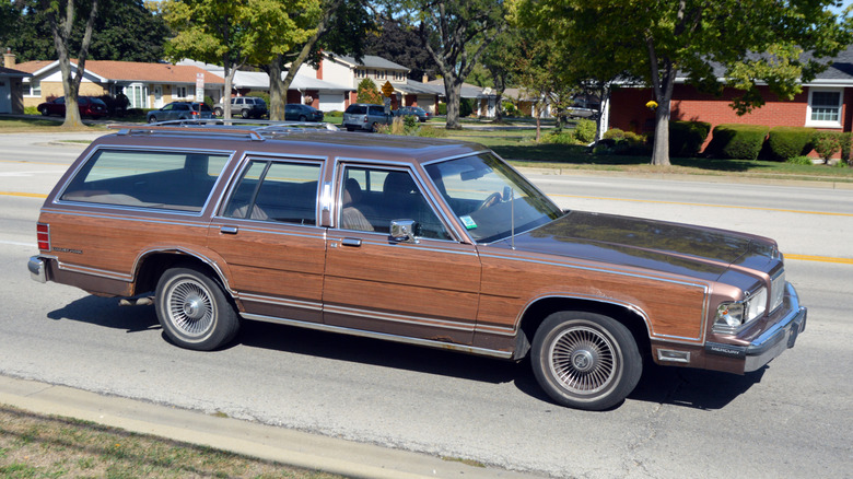 Side view of full-size Mercury station wagon driving in residential area.