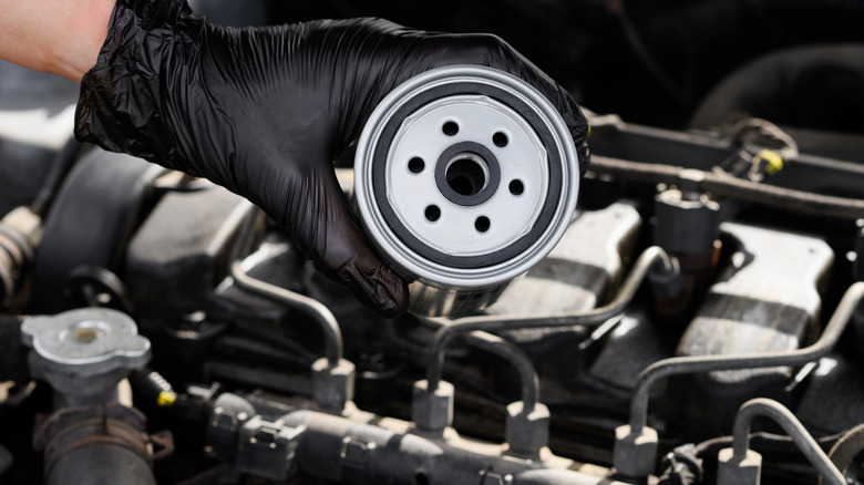 An auto mechanic holding fuel filter for a diesel engine