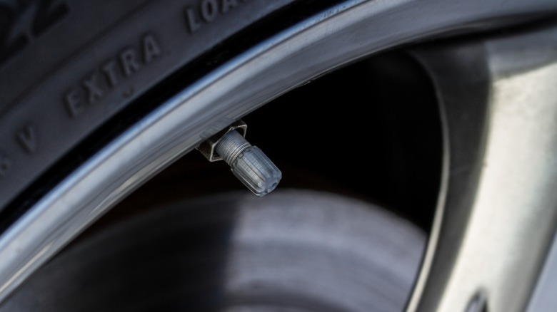 A closeup image of a car wheel showing the valve stem and cap