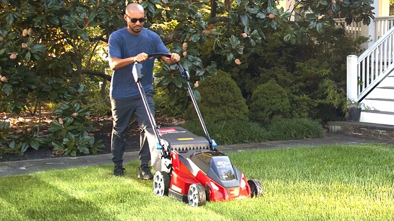 Person pushing Toro lawn mower in yard