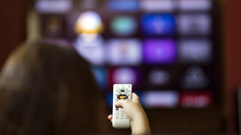Person using universal remote control for television