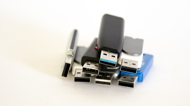 A collection of several usb thumb drives of different colors, stacked on top of one another