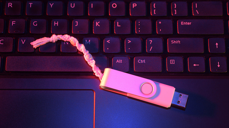 A usb thumb drive with a lanyard attached to it, sitting on a keyboard