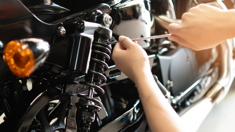 Hands repairing a rear shock on a motorcycle