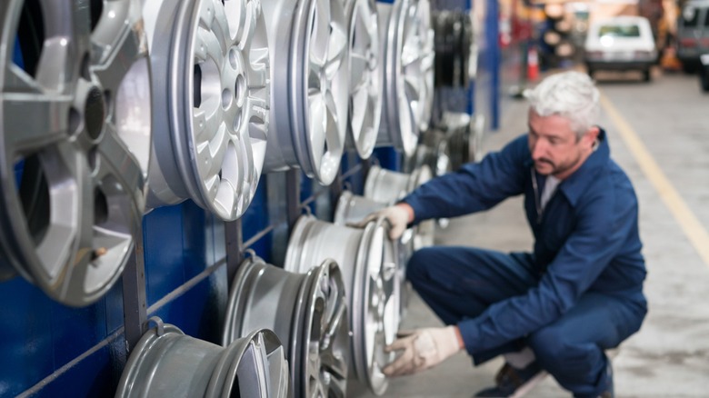 A person looking at car rims mounted on a wall