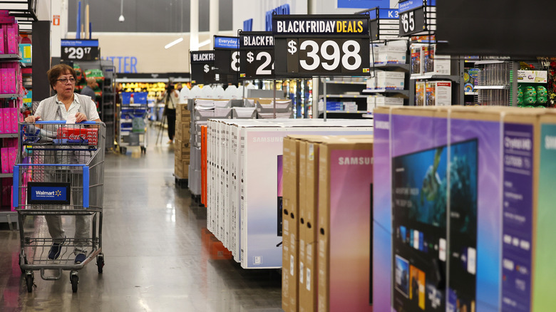 Una compradora empuja un carrito mientras camina por el pasillo de TV en Walmart el Black Friday.