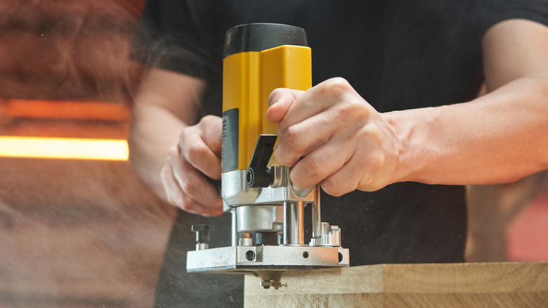 A Man Using A Wood Router Around The Edge Of Project Material