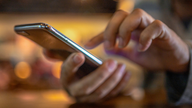 Closeup image of a person holding and using a smartphone.
