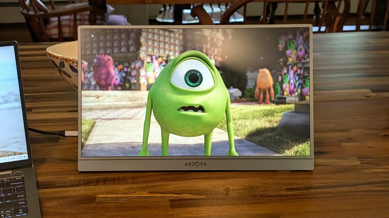 Arzopa Z1FC Grey Portable Monitor showing a scene from "Monsters Inc." on a wooden table.
