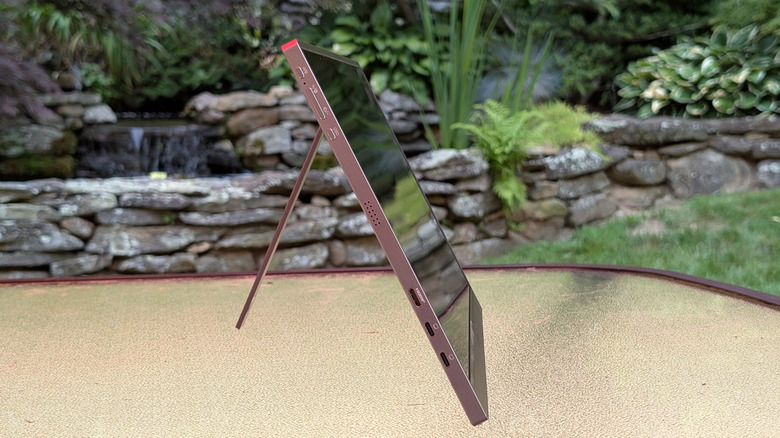 Arzopa Z1FC Grey Portable Monitor on a glass table with a stone waterfall behind it showing its port and button selection