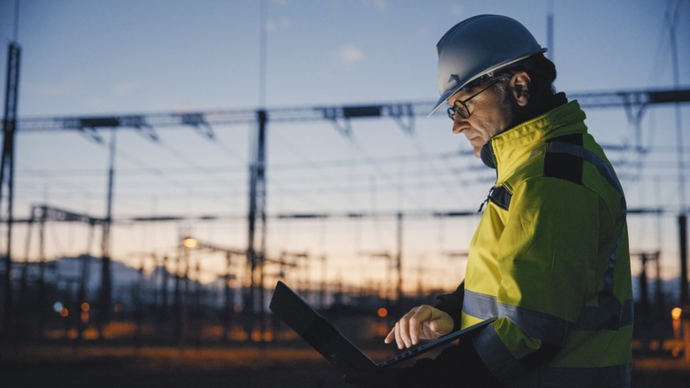 An engineer using a laptop at a dark power plant