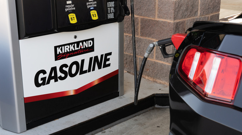 A black car filling up with gas at a Costco gas station.