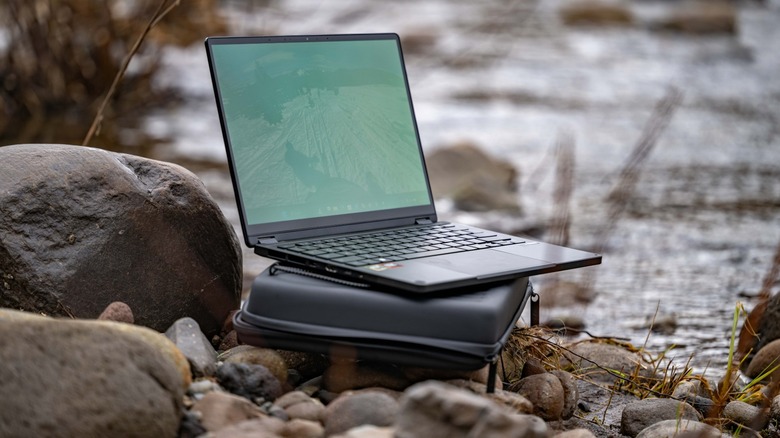 The ASUS GoPro edition laptop on top of its case in the rocks by the river.