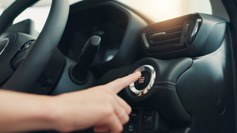 A close up of a hand about to a car's start button