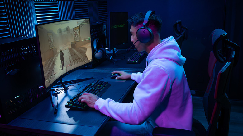 Gamer sitting at desk playing while wearing Audeze Maxwell gaming headset