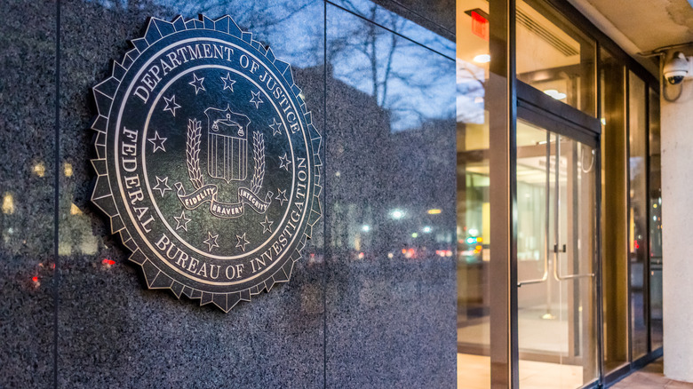 A close-up of the FBI logo in marble on the front of a building near an entranceway