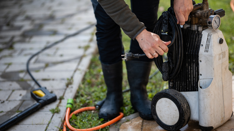 A man holding the power cord of a pressure washer