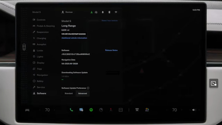 A close-up of a Tesla Model S touchscreen showing a software update in progress.