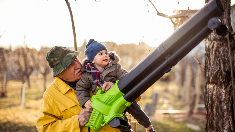 old man and child holding leaf blower