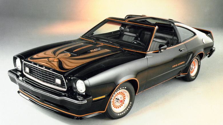 Black and gold 1978 Ford Mustang King Cobra on gray background