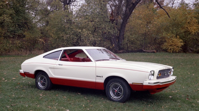 Right-side view of a red and white1976 Ford Mustang II parked on grass