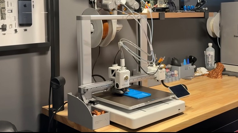 A Bambu Lab A1 3D printer on a workbench.