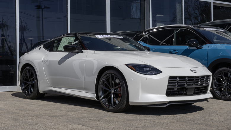 A white new Nissan Z parked in front of a dealership.