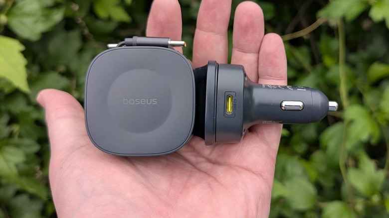Baseus PrimeTrip VR2 Max held in hand in front of green leaves.