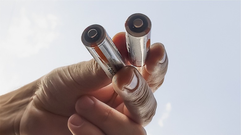 Two AA batteries held by hand