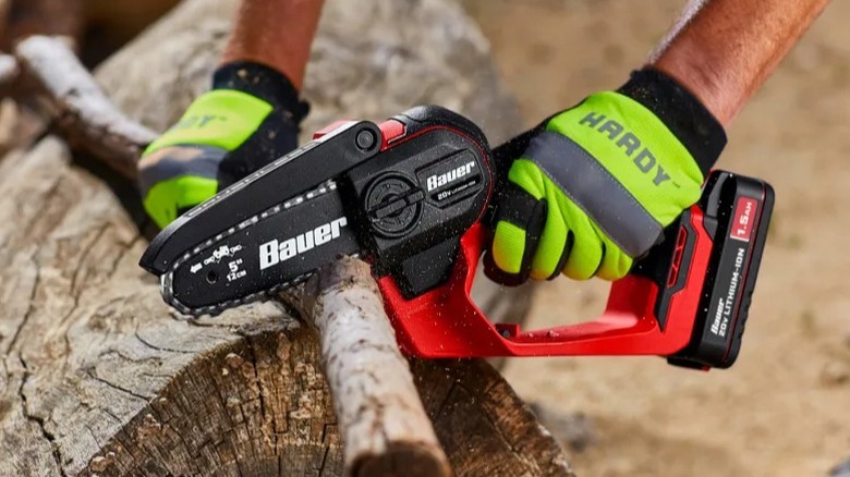 Person cutting branch with Bauer hand chainsaw