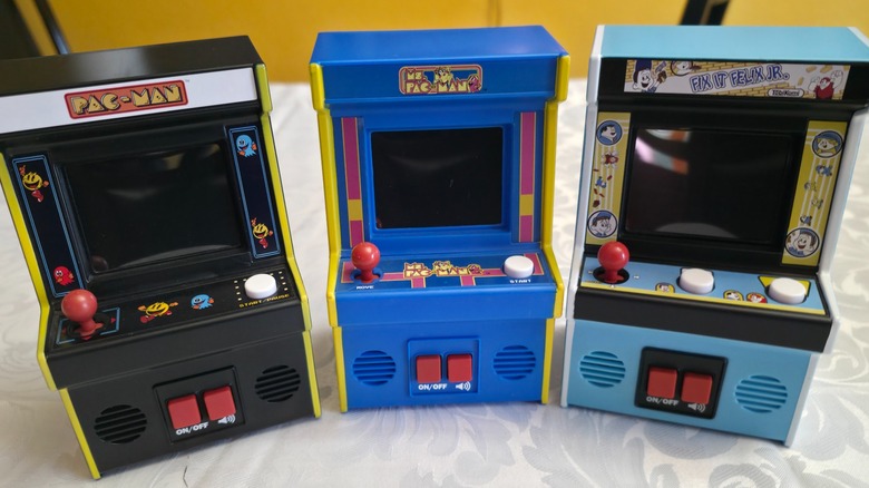 Three Basic Fun mini arcade machines sitting atop a white tablecloth