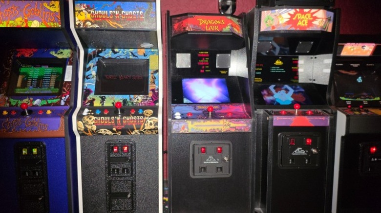 A row of 1:6 mini arcade machines by New Wave Toys arranged on a shelf