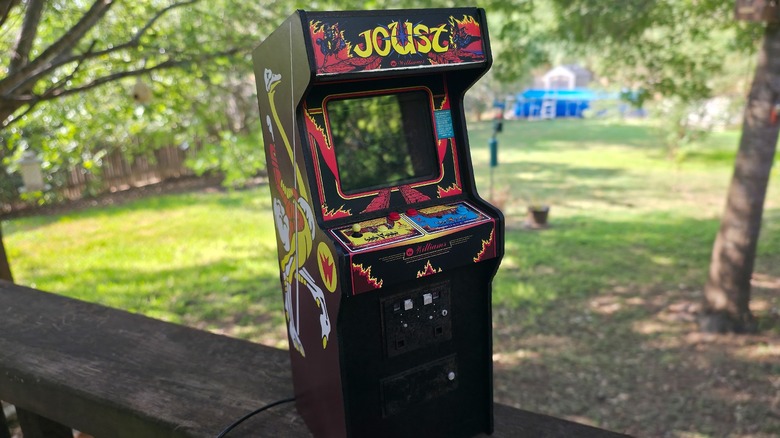 Joust miniature arcade machine on wood outdoors.