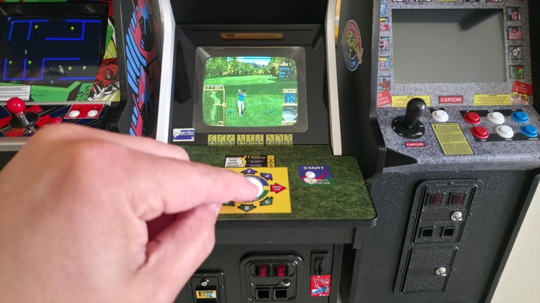 A hand playing with the controls for the New Wave Toys Golden Tee game