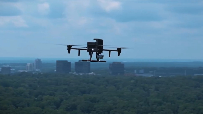 A Flock Safety drone in the air with a city in the distance