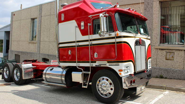 A red and white vintage Kenworth semi truck on display outside a building