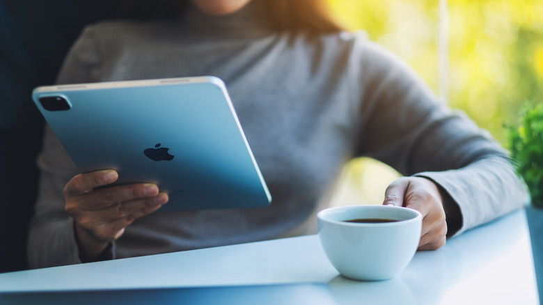 person holding iPad Pro and coffee 