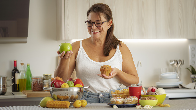 woman choosing between apple or muffin