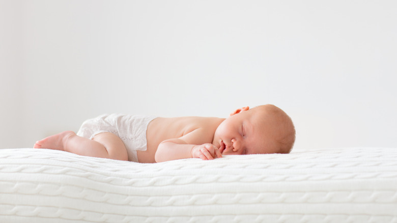 Adorable baby in white sunny bedroom.
