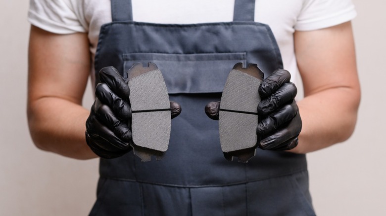 A person holding two new car brake pads