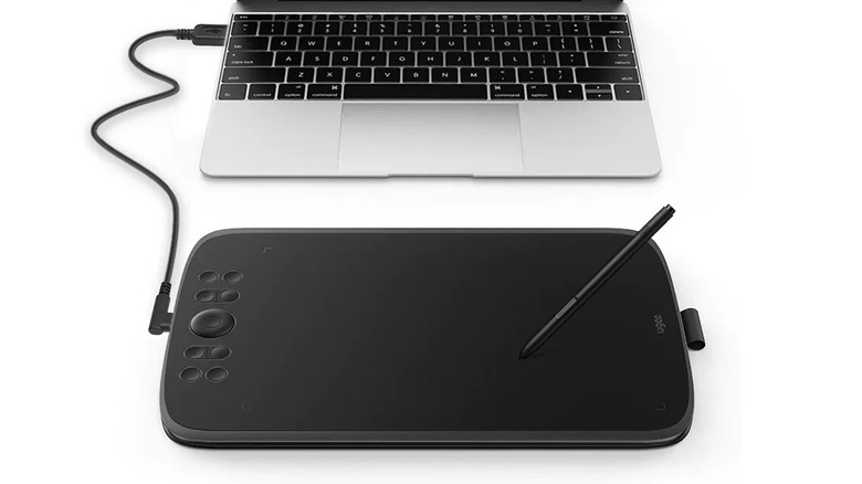Ugee tablet and stylus connected to laptop on white background