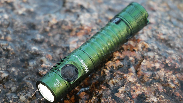 A Wurrkos FC11C flashlight laying on some wet rocks