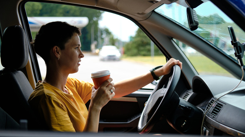 Person sitting in a car with a hand on the steering wheel