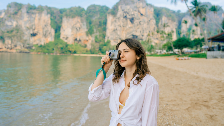 woman holding camera on beach