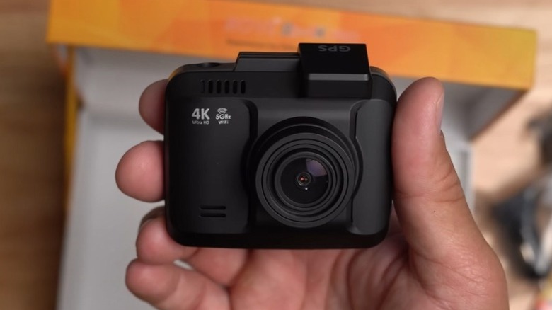 Hand holding a Rove R2-4K Pro dashcam with the Rove box in the background