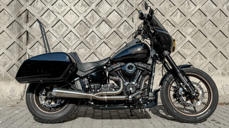 A Harley FXLRS Low Rider S114 bike parked at the side of a street in front of a brick wall
