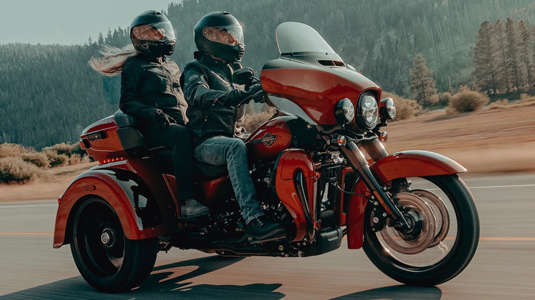Two bike riders on red Harley-Davidson Tri Glide Ultra