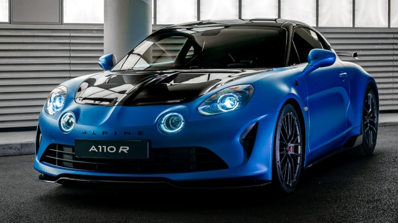 Blue Alpine 110 R parked on asphalt in front of a white column and walls