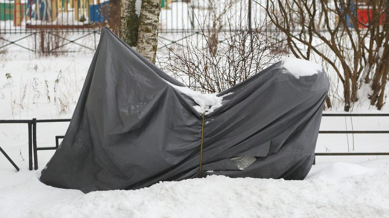 Motorcycle parked in the snow with a cover on